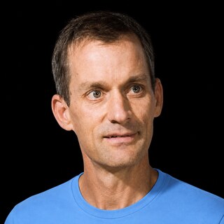 AI-generated portrait of Jeff Dean wearing a DoomBench-blue top against a black background.